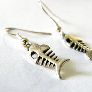 May include: A pair of silver fish bone earrings. The earrings are dangle style and feature a detailed fish bone design.