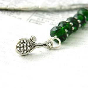 May include: A silver tennis racket charm with a green crystal bead keychain.