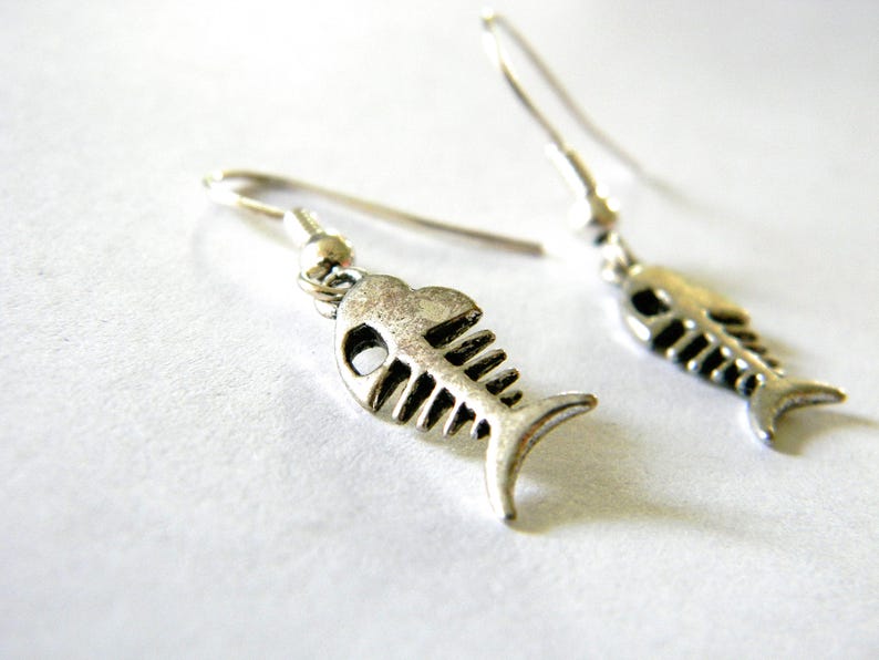 May include: A pair of silver fish bone earrings. The earrings are dangle style and feature a detailed fish bone design.