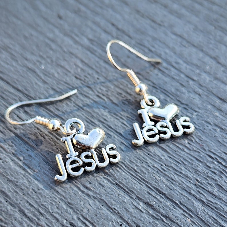 Pu&ograve; includere: Orecchini d'argento con un cuore e le parole "I Love Jesus".