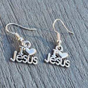Pu&ograve; includere: Un paio di orecchini d'argento con un cuore e le parole "I love Jesus" che pendono dal fondo.