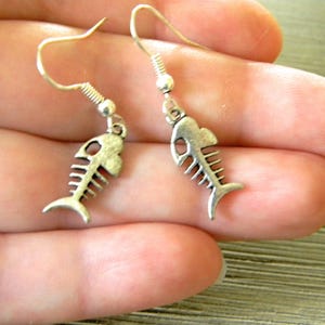 May include: A pair of silver fish bone earrings. The earrings are dangle style with a hook closure.