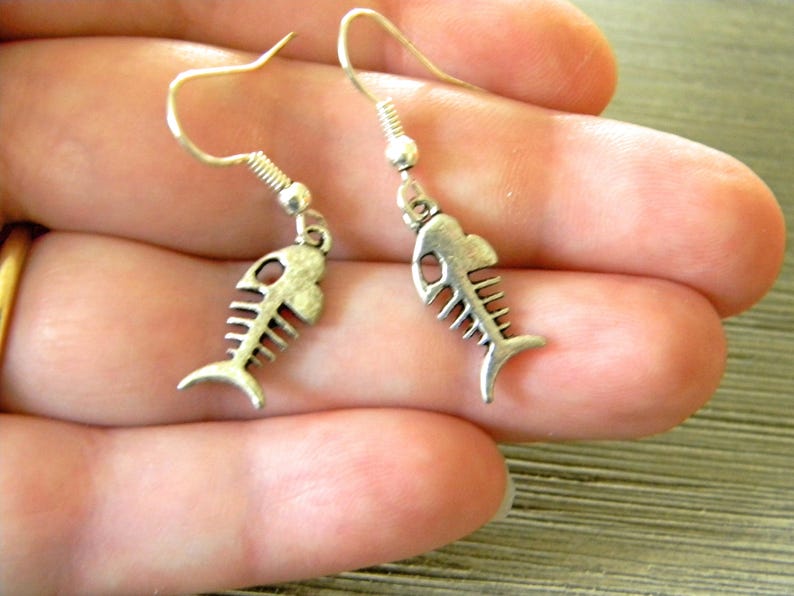 May include: A pair of silver fish bone earrings. The earrings are dangle style with a hook closure.