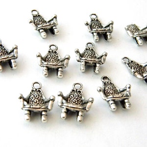May include: Ten silver-toned metal charms shaped like ornate chairs. Each charm has a loop at the top for attaching to a necklace, bracelet, or other jewelry.