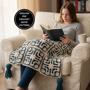 以下が含まれることがあります： クリーム色の肘掛け椅子に座り、本を読んでいる人が、クリーム色とティール色の鉤針編み毛布に覆われています。毛布は幾何学模様で、ティール色のタッセルが付いています。画像には「ENGLISH PDF CROCHET MOTIF PATTERN」と書かれた円形のグラフィックが含まれています。