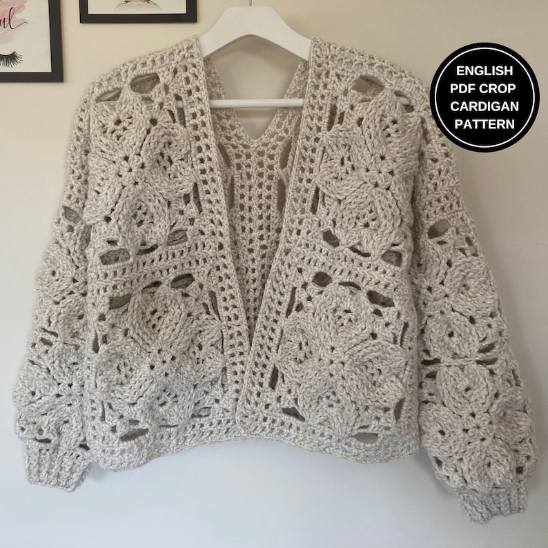 May include: A crocheted cardigan with a lacy pattern in a light beige color. The cardigan has a V-neck and long sleeves. The text "ENGLISH PDF CROP CARDIGAN PATTERN" is visible in the upper right corner of the image.
