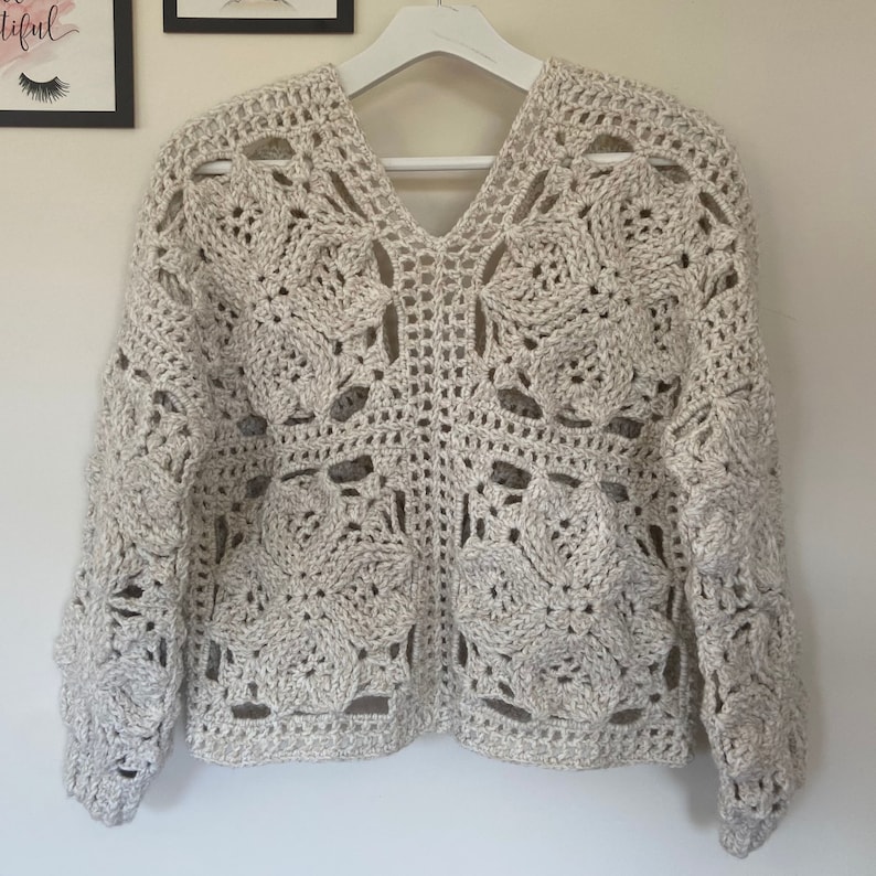 May include: A beige crocheted sweater with a V-neck and long sleeves. The sweater has a delicate openwork pattern.