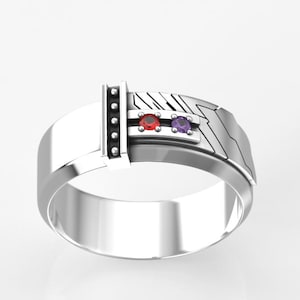 May include: A silver ring with a geometric design. The ring features a red and a purple gemstone. The ring has a rectangular design on one side and a series of small, round accents on the other.