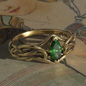 May include: A gold ring with a green emerald gemstone set in a Celtic knot design.