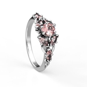 May include: A silver ring with a cluster of pink and clear gemstones set in a floral design.