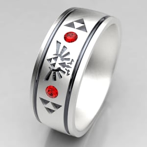 Könnte beinhalten: Ein silberner Ring mit schwarzen Akzenten und roten Edelsteinen. Der Ring hat eingravierte geometrische und stilisierte Designs. Das Design des Rings umfasst Dreiecke, ein Wappen und zwei rote kreisförmige Edelsteine. Der Ring ist ein Schmuckstück.