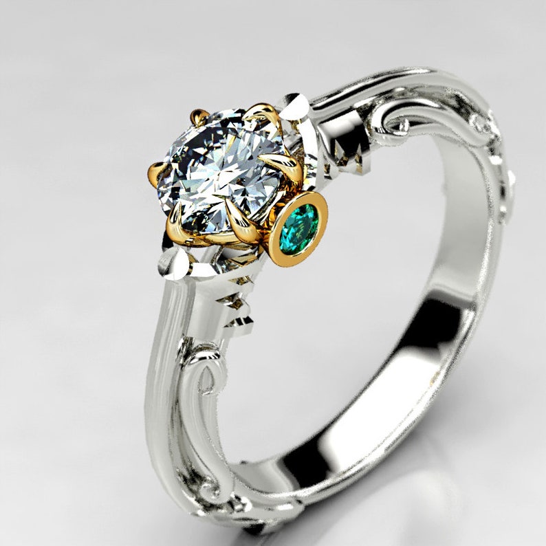 May include: A silver and gold engagement ring with a large, clear diamond and a smaller, green emerald stone.