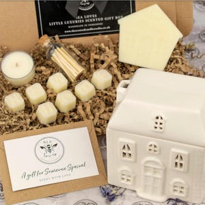 May include: A gift box set for a home fragrance diffuser. The set includes a white ceramic house-shaped diffuser, a small jar of wax melts, a pack of matches, and a card that says "A gift for someone special, sent with love".