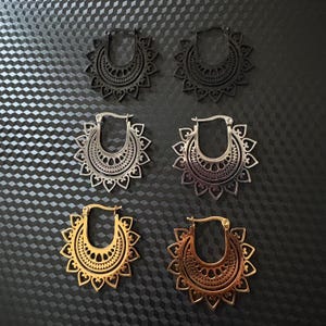 Könnte beinhalten: Sechs Paar Creolen mit filigranen Mandala-Mustern. Die Ohrringe sind aus Metall und in drei verschiedenen Ausführungen erhältlich: Silber, Gold und Schwarz.