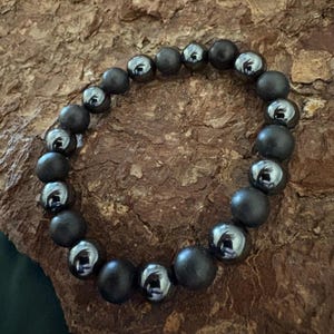 Könnte beinhalten: Ein Armband aus schwarzen matten und silbernen glänzenden Perlen.
