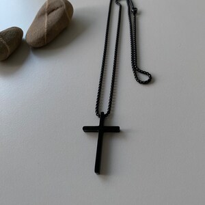 May include: A black chain necklace with a black cross pendant.