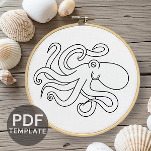 Pode incluir: Um desenho de polvo em preto está centrado em tecido branco esticado dentro de um bastidor de bordado de madeira. As palavras "PDF TEMPLATE" são impressas em preto em um círculo cinza no canto inferior esquerdo. Conchas espalhadas.