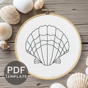 May include: A black line drawing of a seashell is centered on white fabric stretched within a wooden embroidery hoop. The text "PDF TEMPLATE" is printed in black at the bottom. Seashells are scattered around the hoop on a wooden surface.