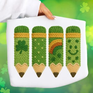 Peut inclure: Quatre crayons verts avec des textures tricotées, chacun avec des motifs sur le thème de la Saint-Patrick. Un crayon a un trèfle, un autre a des pois, un troisième a un arc-en-ciel et le dernier a un smiley. Les crayons ont des pointes beiges et des accents jaunes et beiges.