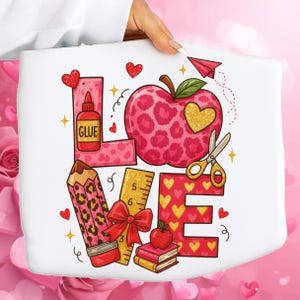Puede incluir: Bolso tote blanco con la palabra "LOVE" compuesta por elementos escolares. La "L" es una regla, la "O" es una manzana con un corazón, la "V" es un lápiz y la "E" es una regla. El diseño incluye corazones, pegamento, tijeras y un avión de papel.
