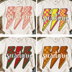 May include: Four white t-shirts with the word "secretary" in cursive script. Each shirt features a different color scheme for the lightning bolt graphic: pink and red, yellow and pink, green and red, and orange and brown.