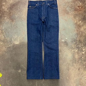 May include: Dark blue denim jeans with a classic five-pocket design. The jeans have a straight leg cut and a button and zip closure. The fabric appears to be a medium-weight denim. The jeans are displayed on a neutral background.