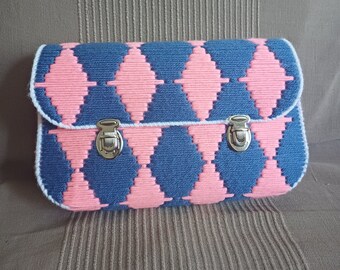 Puede incluir: Una bolsa de tejido tejido rosa y azul con dos cierres metálicos. La bolsa tiene un patrón de diamante.