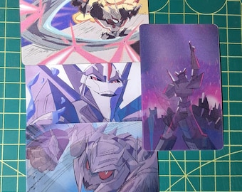 May include: Four trading cards with robot character illustrations. The cards showcase action poses with dynamic lines and a colour scheme of blues, purples, and reds. One card features a robot silhouetted against a cityscape.