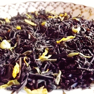 May include: A close-up of a blend of black tea leaves, dried citrus peel, and white tea pearls. The tea is loose leaf and ready to be brewed.