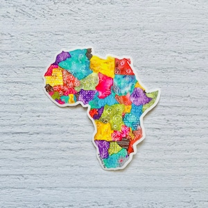 Op de afbeelding: Een kleurrijke sticker van het Afrikaanse continent met een patchwork-ontwerp. De sticker bevindt zich op een witte houten achtergrond. De tekst "A fearless life" staat onderaan de sticker.