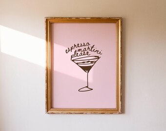 May include: A framed print with a pink background and a brown illustration of a martini glass. The words "espresso martini please" are written above the glass in a cursive font. The frame is gold.
