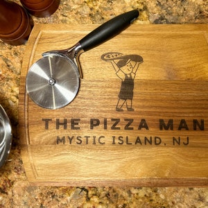 May include: A wooden cutting board with a pizza cutter and a design of a cartoon pizza man holding a pizza. The board is engraved with the text "The Pizza Man Mystic Island, NJ".