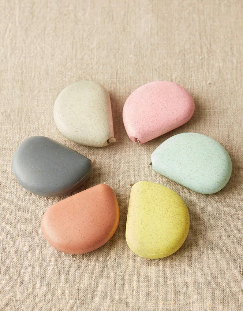 Flat lay of Cocoknits tape measures in clay and linen tones paired with other soft pastel options.