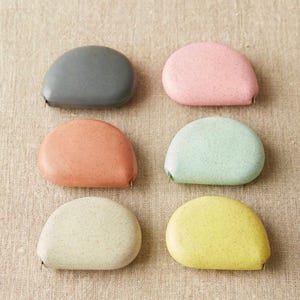Full color set of Cocoknits tape measures, showcasing soft clay, mint, gray, yellow, pink, and linen tones.
