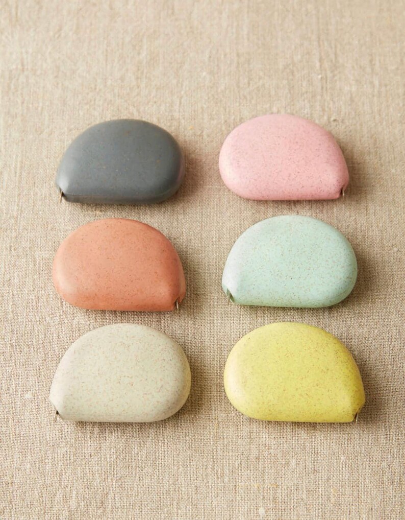 Full color set of Cocoknits tape measures, showcasing soft clay, mint, gray, yellow, pink, and linen tones.