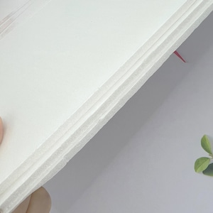 May include: Close-up of a white foam board with multiple layers. The board is held at an angle, revealing the layers.