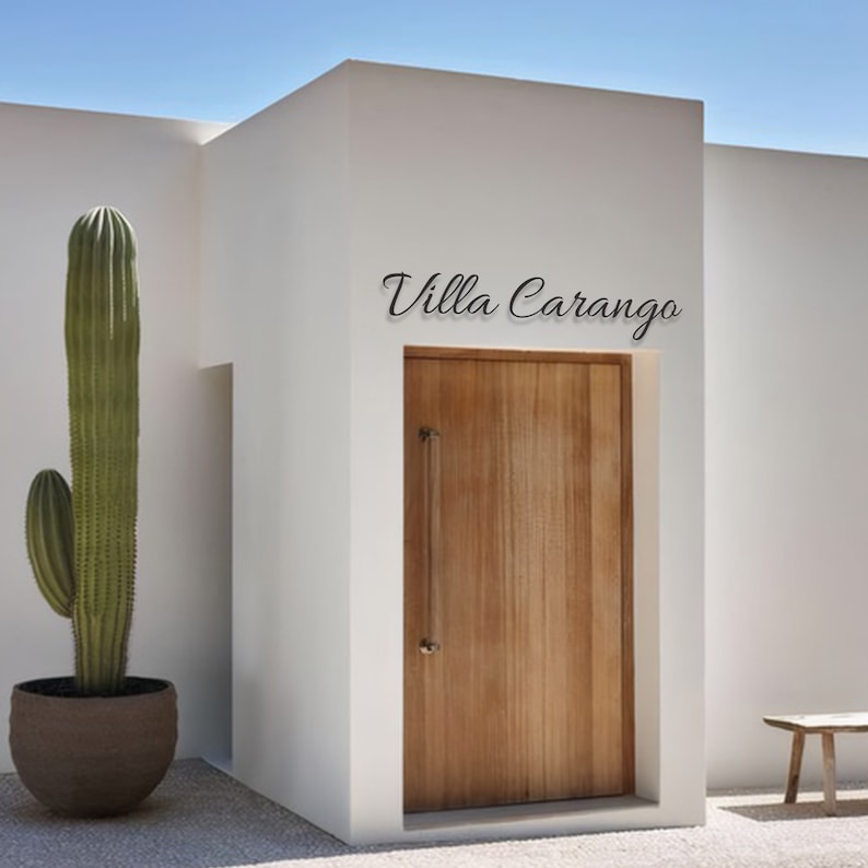 May include: A white building with a wooden door and the text "Villa Carango" above the door. A large cactus is in the foreground.