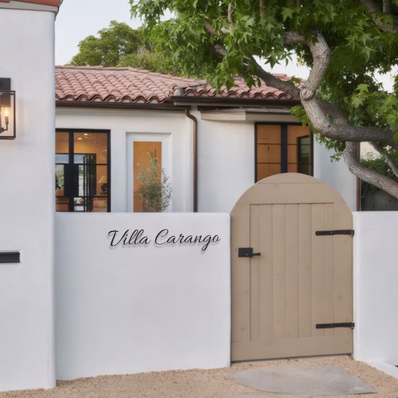 May include: A white house with a brown tiled roof and a wooden gate with the words "Villa Carango" written on the wall.