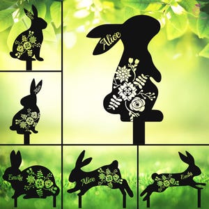May include: Six black metal silhouette garden stakes featuring bunnies with floral designs. The bunnies are in various poses, including standing, sitting, and hopping. Each stake has a personalised name, including "Alice" and "Emily".