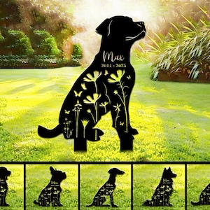 Könnte beinhalten: Schwarze Metall-Hunde-Silhouette mit floralen und Schmetterlings-Ausschnitten. Der Name des Hundes, "Max", und die Daten "2014-2025" sind abgebildet. Das Bild zeigt auch mehrere kleinere Hunde-Silhouetten mit ähnlichen Designs.