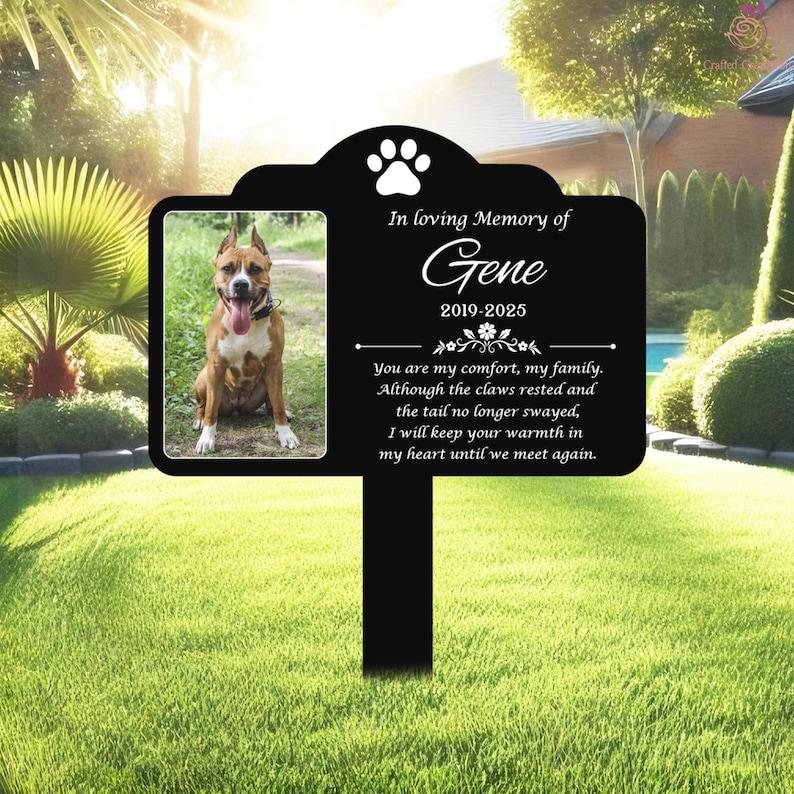 K&ouml;nnte beinhalten: Ein schwarzer Gedenkpfahl f&uuml;r Haustiere mit einem Foto eines Hundes und dem Text "In loving Memory of Gene 2019-2025". Der Pfahl enth&auml;lt einen Pfotenabdruck und eine herzliche Botschaft.