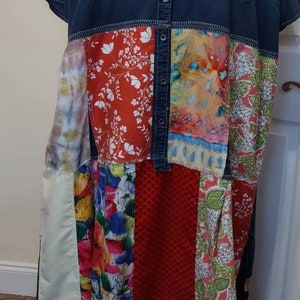 May include: A denim shirt dress with a patchwork skirt. The skirt is made of different fabrics with floral and geometric patterns in shades of red, blue, green, and white.