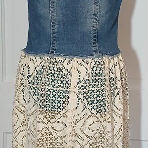 May include: A denim vest with a crocheted lace skirt. The skirt has a fringe hem and is a cream color.