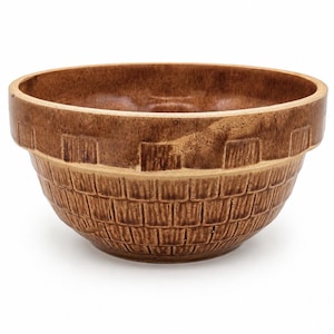 May include: A round, brown ceramic mixing bowl with a glossy finish. The exterior features a textured, grid-like pattern resembling a woven basket, with a smooth, solid band encircling the upper rim. The interior is smooth and deep.