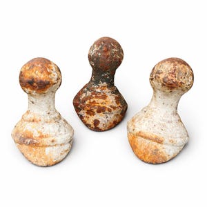 Op de afbeelding: Drie antieke, verweerde metalen decoratieve objecten met een bolvormige bovenkant en een afgeronde basis. De objecten hebben een versleten, verouderde uitstraling met een mix van witte, bruine en oranje roestachtige kleuring. De objecten zijn waarschijnlijk vintage of hergebruikt.