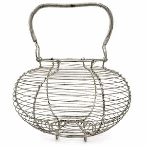 Könnte beinhalten: Ein Vintage-Eierkorb aus Draht mit rundem Körper und gebogenem Griff. Der Korb besteht aus silberfarbenem Metalldraht mit einem stabilen Griff zum Tragen. Der Korb hat ein klassisches Design, ideal zum Sammeln oder Präsentieren von Eiern.