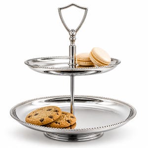 May include: A two-tiered silver serving tray with a handle. The top tier holds two macarons, and the bottom tier has two chocolate chip cookies. The tray has a beaded edge and a decorative handle.