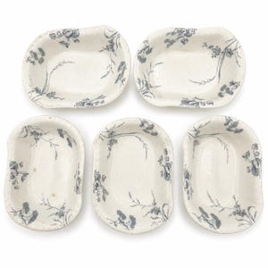 May include: A set of five oval-shaped ceramic dishes featuring a cream-coloured base with a delicate dark grey floral pattern. Each dish has a scalloped edge and a deep basin, displaying a consistent botanical design across the entire collection.