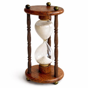 May include: A classic hourglass with a wooden frame and clear glass bulbs. The hourglass contains white sand, and the wooden frame has a dark brown finish. The hourglass is supported by four wooden legs and has brass accents.
