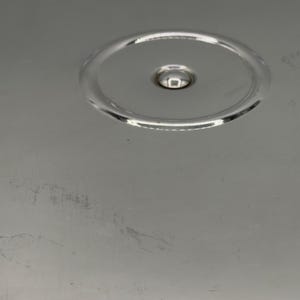 Op de afbeelding: Een gepolijst zilverkleurig metalen oppervlak met een cirkelvormige inkeping in het midden bovenaan. Het gladde, reflecterende materiaal vertoont subtiele krassen en lichte schaafplekken over het onderste deel van de metalen plaat.